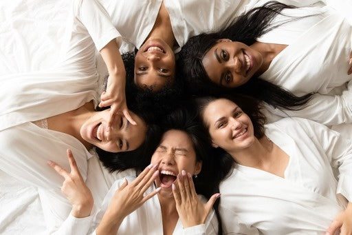 A group of women laying on the ground with their mouths open.