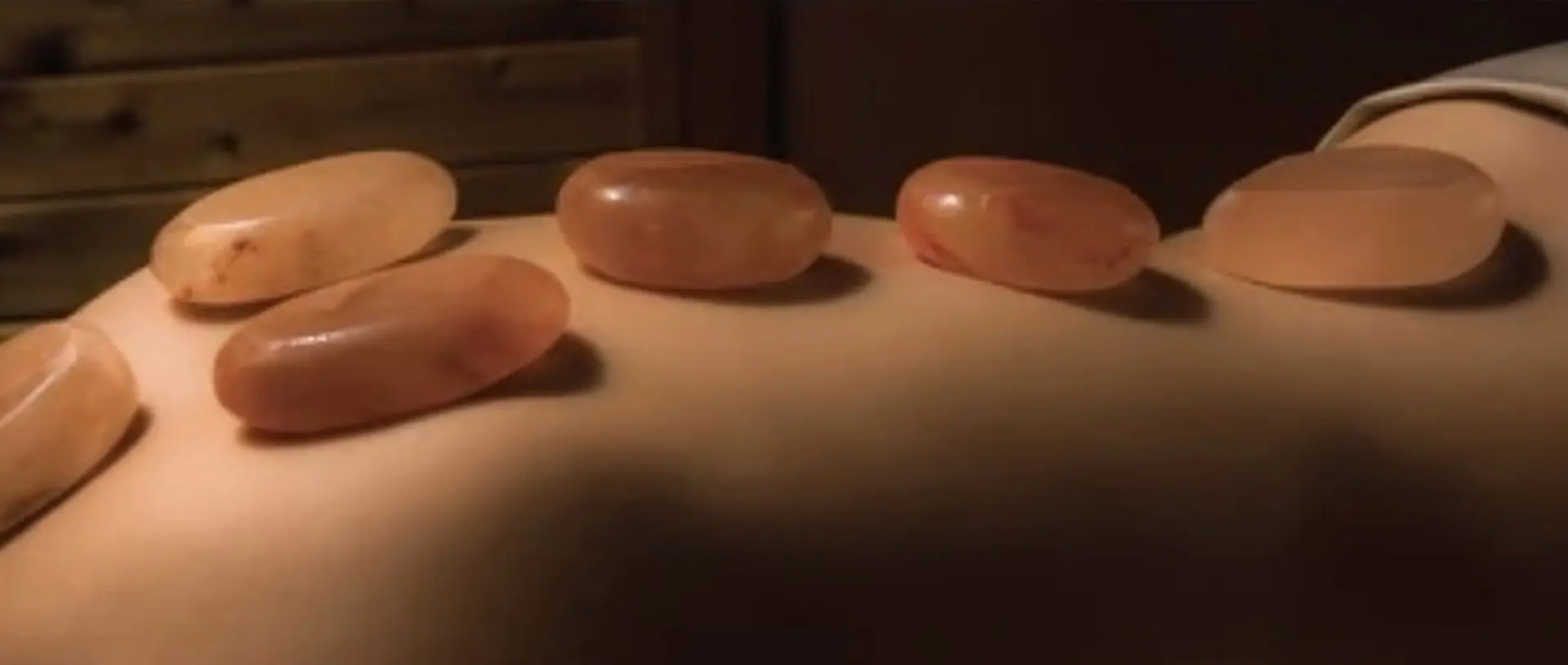 Three pink stones sitting on top of a person 's arm.